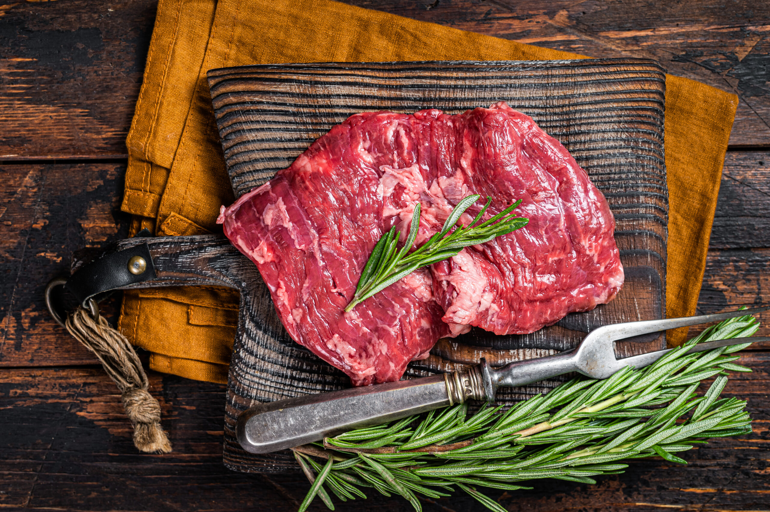 Raw alternative skirt beef steak on butcher board. Wooden backg